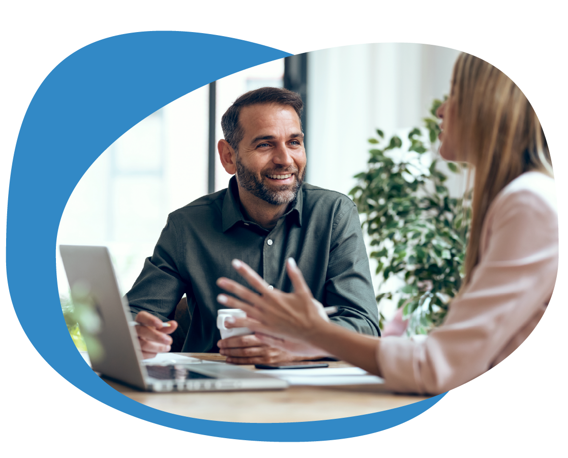 A bearded man and blonde woman in a business meeting with laptop and discussion.